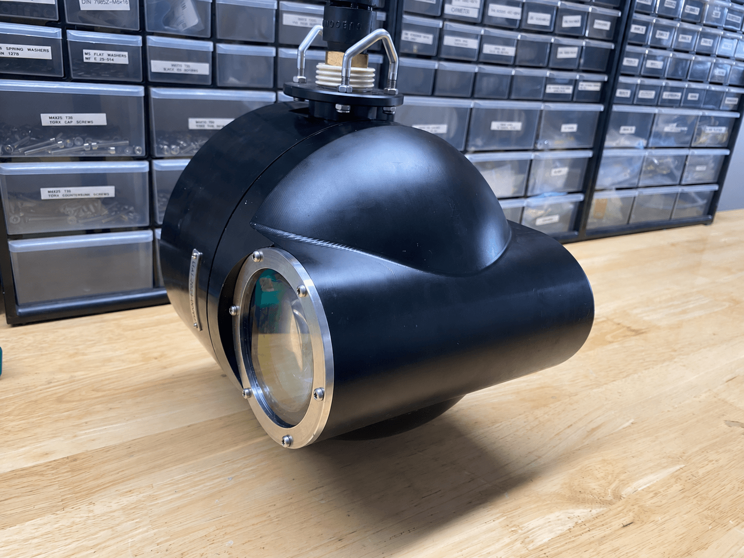 Black underwater imaging instrument with a circular lens on a workshop table